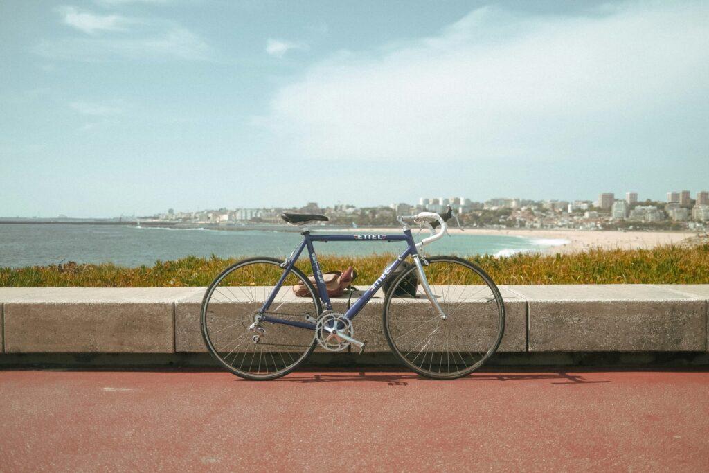 A road bike parked along a coastal path with the beach behind